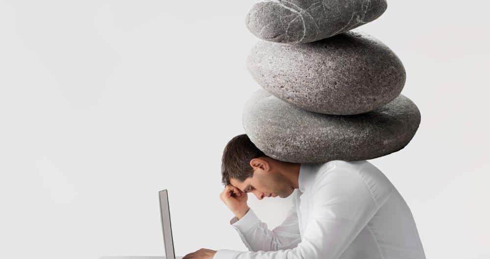 Hombre con piedras sobre sus hombros para dramatizar el peso de la ansiedad
