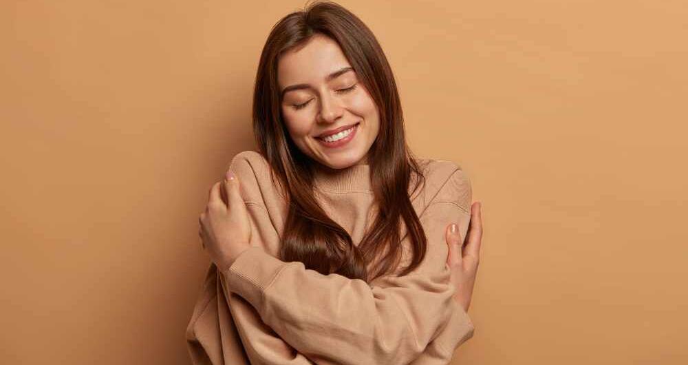 Mujer se abraza feliz para los 6 pilares de la autoestima