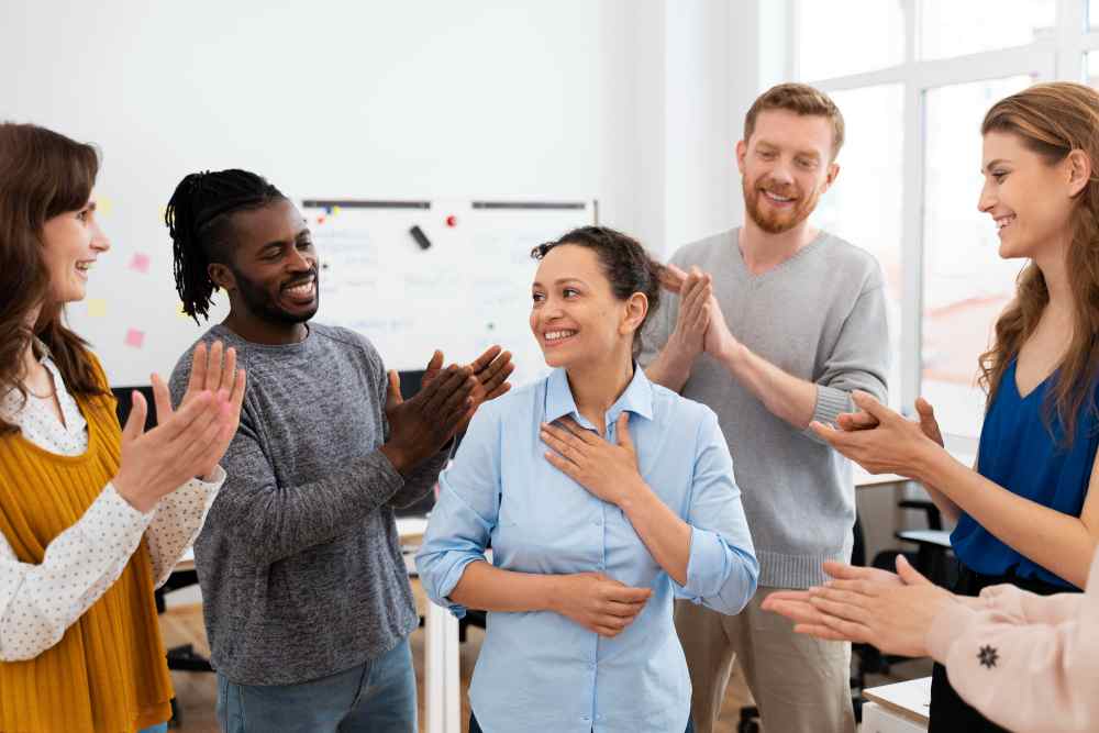 Compañeros de oficina felicitan a mujer que recién expuso aplicando Técnicas para Hablar en Público
